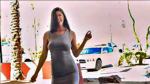 Amber Hahn in tight gray dress, smiling outdoors