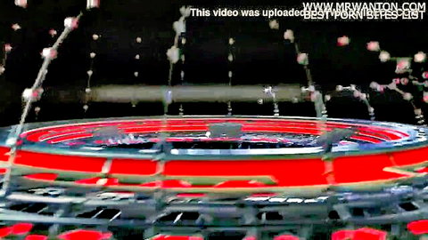 Blurry red circular stage with spraying water jets in dark arena