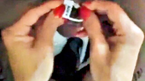 Blurry close-up of hands holding a tagged red object in cuckold tutorial