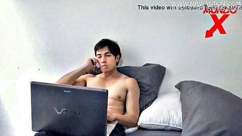 Shirtless Asian man on bed using laptop and phone in Ella's sexy house sale scene