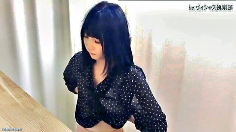 Petite Japanese babe with small perky tits and hard nipples visible through sheer black polka dot blouse leaning on table