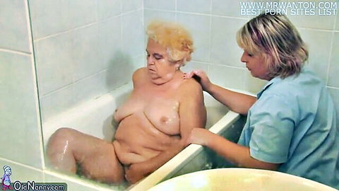 Chubby naked granny with saggy tits bathed by nurse in steamy bathtub