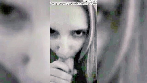 Blurry closeup of blonde amateur MILF sucking cock with pursed lips and intense eyes.