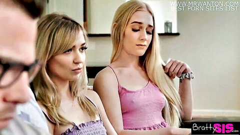 Two blonde stepsisters in skimpy tops sitting closely on couch with stepbrother watching