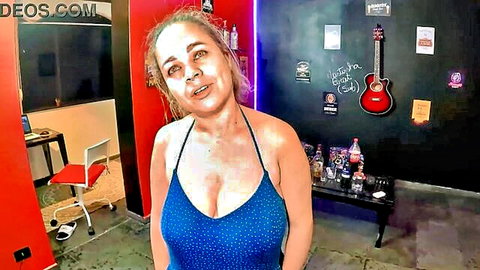 Busty blonde MILF in tight blue dress showing deep cleavage and huge tits