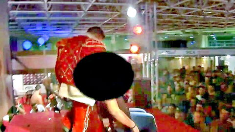 Man in shiny red jacket stripping on crowded stage at public party with censored butt exposed