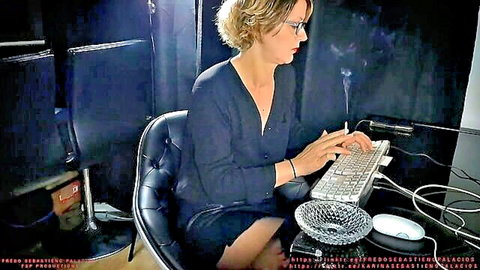 Slutty blonde boss in glasses smokes seductively at office desk