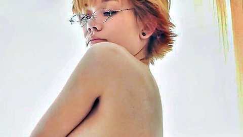 Topless petite redhead teen with glasses looks back covering tiny tits