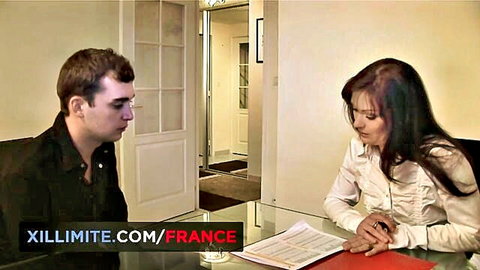 Brunette woman in white blouse sits at desk with male colleague in office