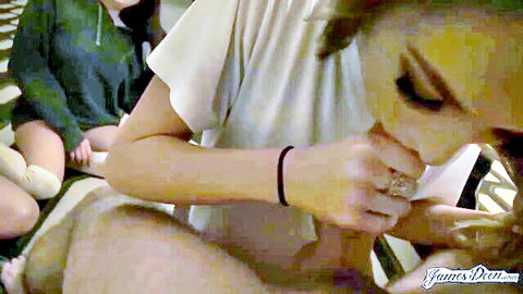 Short-haired brunette teen sucks thick cock deeply while friend watches on couch