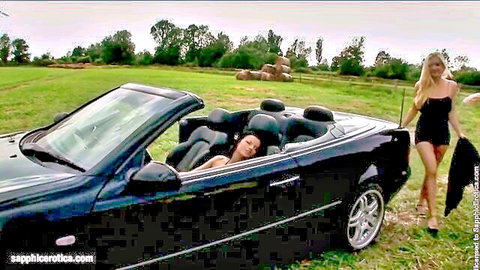 Blonde in short black dress by convertible with relaxed brunette in sensual lesbian rendezvous