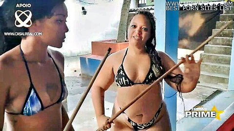 Morango RJ and Alerquina in skimpy bikinis holding spears outdoors