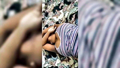 Indian MILF lying on bed with striped top pulled up exposing big brown tits and nipples