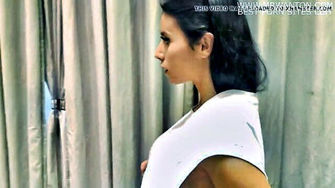 Brunette woman in white top exposing side boob in changing room