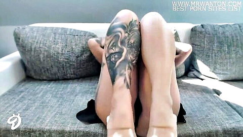 Tattooed amateur spreads legs wide on couch exposing shaved pussy in black lingerie high heels