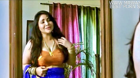 Curvy Indian MILF in orange blouse and blue saree smiling with deep cleavage tease