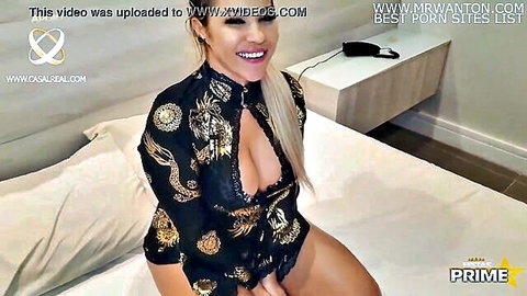Curvy tanned blonde with massive tits in revealing dragon lingerie teasing on bed