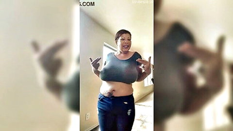 Busty mature woman teases big tits with peace sign pose in tight top and jeans