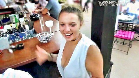 Blonde woman in low-cut white dress laughing at swingers club bar