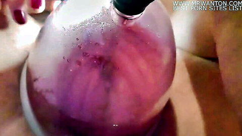 Closeup of swollen pussy inside clear pussy pump filled with purple fluid