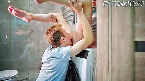 Redhead guy performs cunnilingus on shaved pussy of young flexible teen with legs up high on washing machine