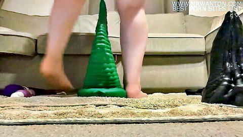 Curvy white woman naked lower body over huge green and black anal dildos