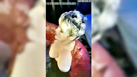 Mature spiky-haired blonde exposes her huge bare tits from pulled-down red top