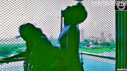 Silhouette of couple in doggy style fuck against chain link fence outdoors