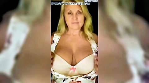 Blonde MILF with massive tits pulls down floral dress revealing deep cleavage in pink bra