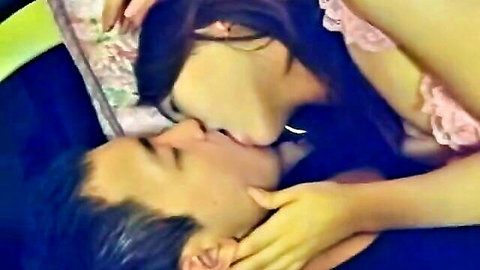 Asian woman in pink lingerie passionately kissing man on bed