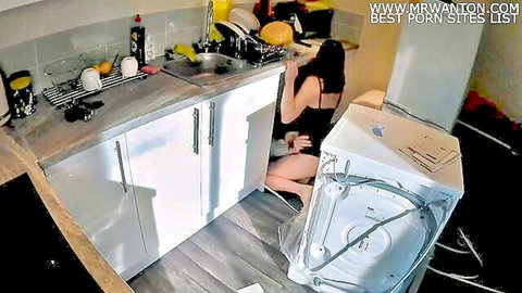 Brunette wife in black dress kneels seductively in kitchen