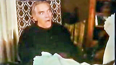 Vintage man in black sweater shouting intensely while seated in ornate chair during retro scene