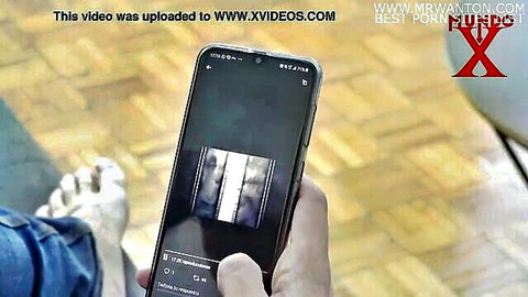 Hand holding phone displaying dark closeup of creampie cum dripping from pussy on Xvideos rough porn video