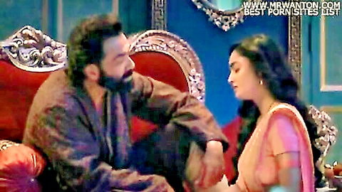 Indian man in robe leans close to woman in pink saree, seductive moment