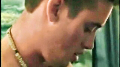 Closeup of young man's pleasured face with gold chain necklace during intense blowjob