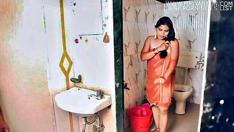 Sexy Indian woman in tight orange towel squeezing wet hair in steamy bathroom tease