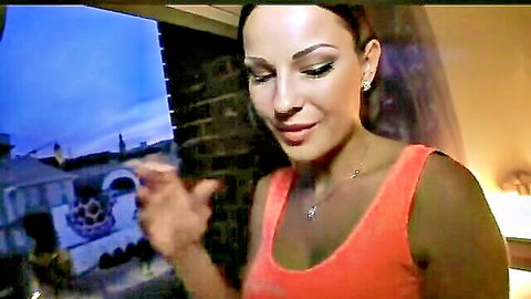 Seductive brunette with huge tits smiling in tight orange tank top showing deep cleavage