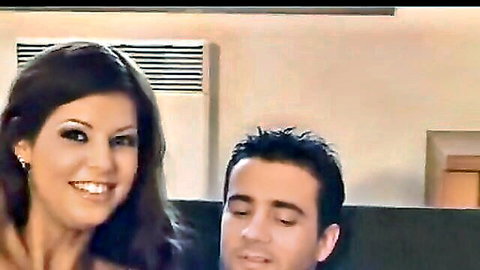 Smiling brunette MILF leaning close to handsome guy on couch in teasing pose
