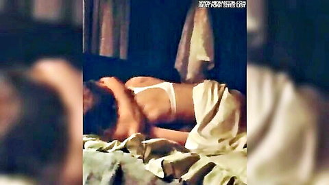 Seductive woman in white bra and sheet on bed, teasing back view