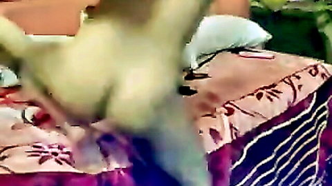 Naked woman spreads legs wide fingering shaved pussy on floral bedspread