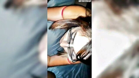 Blurry closeup of brunette woman in glasses lying on bed during intimate encounter, partner recording