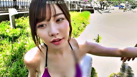 Asian woman in pink bikini smiling seductively outdoors at beach