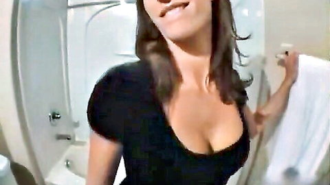 Brunette woman in black dress with deep cleavage in bathroom