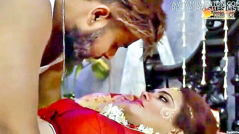 Bearded Indian groom passionately kisses busty bride in red saree with intense eye contact