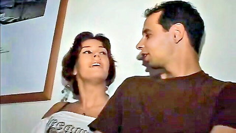 Brunette woman in off-shoulder top gazes up at man in intimate couple preview