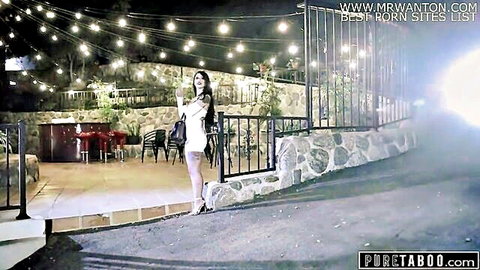 Seductive brunette teen in tight white dress on outdoor motel patio at night