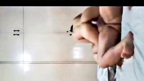 Blurry homemade closeup of brown-skinned woman's bare ass cheeks and feet in tiled bathroom.