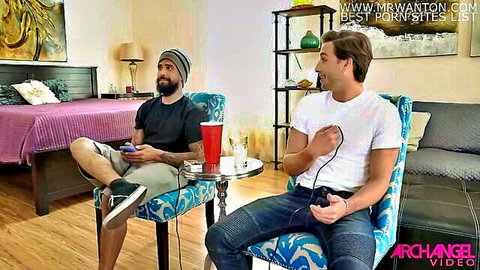 Two bearded gamer guys in t-shirts playing Xbox controllers in bedroom with red solo cup