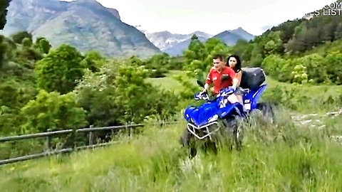 Brunette couple riding blue quad bike outdoors in green mountains