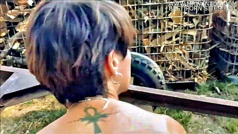 Topless brunette country girl with ankh back tattoo outdoors